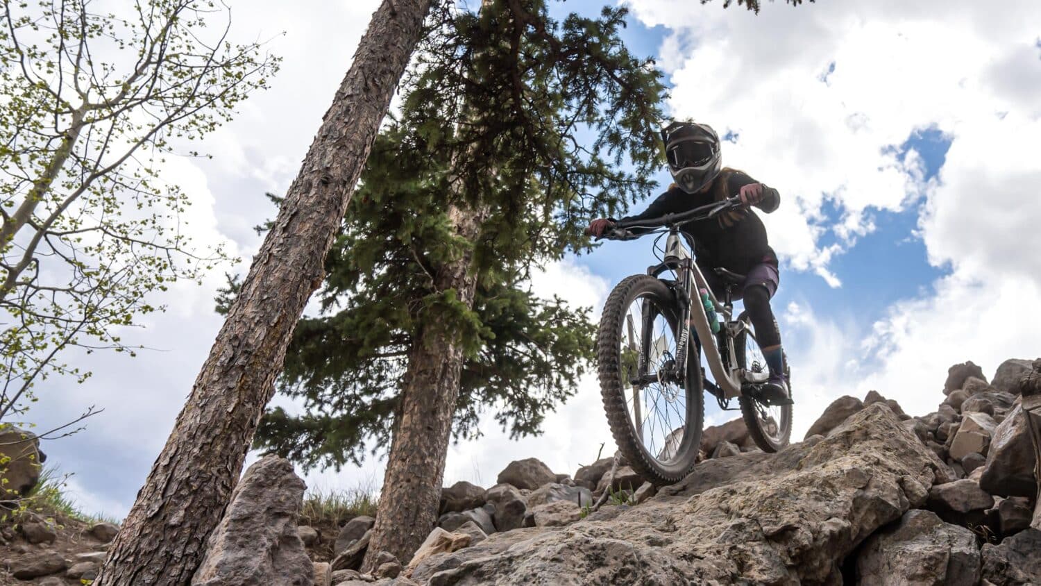 Biker going down a rock at Pajarito Bike Park in New Mexico